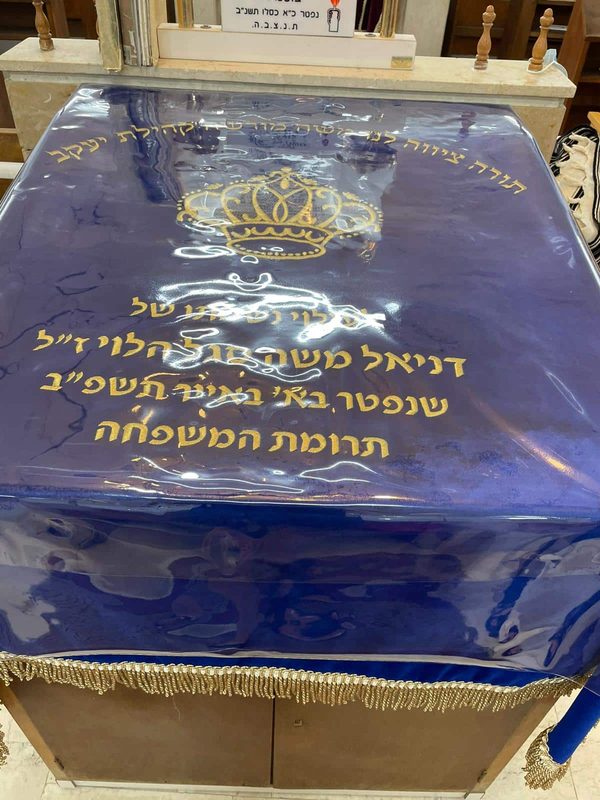 משטחית שקופה מותקנת על שולחן בבית כנסת, מעל כיסוי רקום